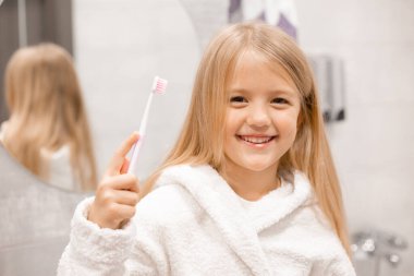 Banyoda dişlerini yıkayan bornozlu tatlı bir kız. 