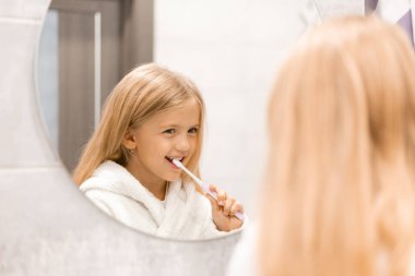 Banyoda dişlerini yıkayan bornozlu tatlı bir kız. 