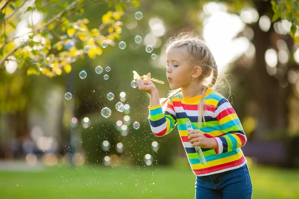 夏日公园里 穿着一件五颜六色的针织衬衫 吹着肥皂泡的小女孩很可爱 — 图库照片