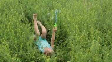 Yeşil yazda küçük mutlu kız sabun köpüğüyle oynuyor.