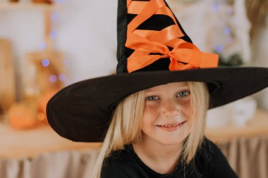 Elinde balkabağı şeklinde bir sepet tutan cadı şapkalı, uzun saçlı küçük sarışın bir kızın portresi. Cadılar Bayramı konsepti Mesaj için yer var. Yüksek kalite fotoğraf