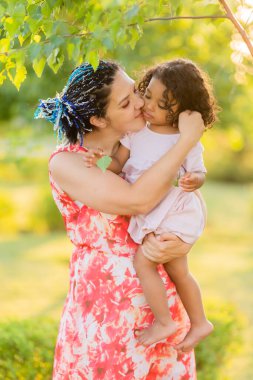 Çok kültürlü bir aile. Anne ve kızı yeşil yaz parkında. 