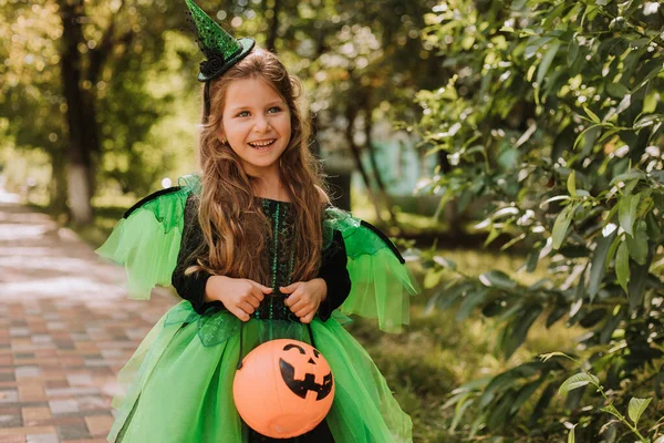 公園でカボチャのバスケットを保持ハロウィンの魔女の衣装でかわいい女の子 屋外で子供 トリックや治療 ハロウィンのコンセプト — ストック写真