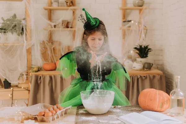 緑のかわいい女の子魔女や妖精のハロウィーンの衣装は カボチャのパイ バームブラック お祝いの装飾されたキッチンで準備します ストック写真