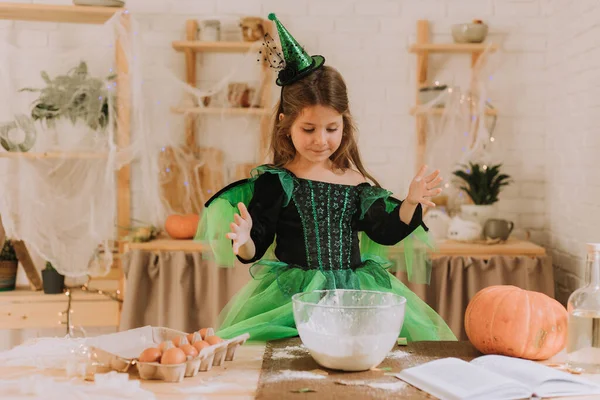 緑のかわいい女の子魔女や妖精のハロウィーンの衣装は カボチャのパイ バームブラック お祝いの装飾されたキッチンで準備します ロイヤリティフリーのストック写真