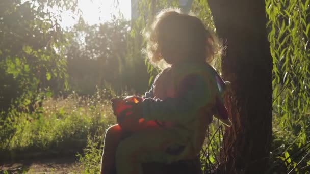 Mała Dziewczynka Tęczowym Stroju Jednorożca Kigurumi Siedzi Drzewie Koszem Dyni — Wideo stockowe