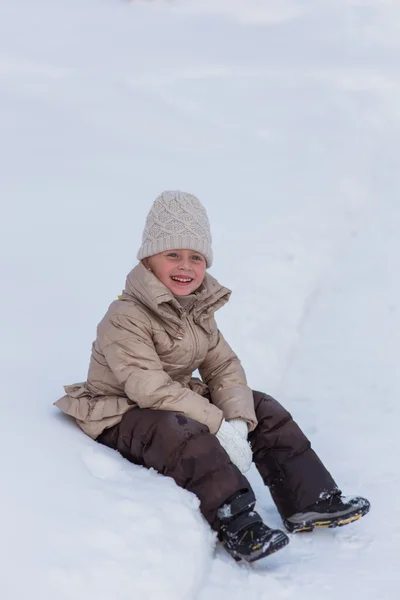 雪の吹き溜まりに冬の女の子が座っています。 — ストック写真