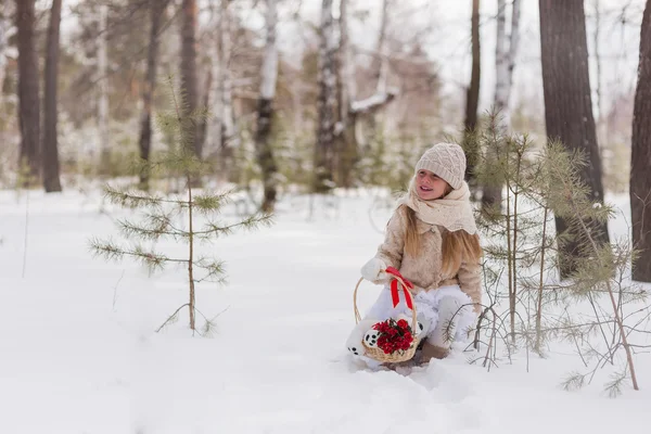 Mädchen im Winterwald mit einem Korb voller Blumen — Stockfoto