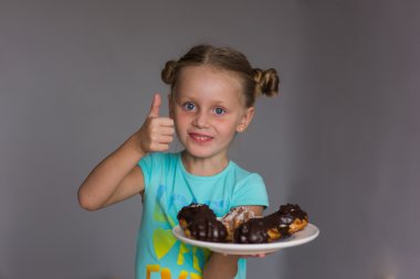 Bazı lezzetli kek bir plaka üzerinde gösterilen bir parmak kadar bir kız tutar