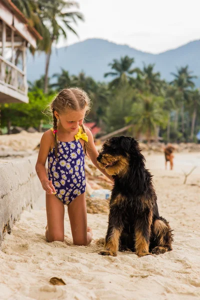 Chica con dos trenzas y se reunió en un traje de baño en la playa cerca del mar perro encantador — Foto de Stock