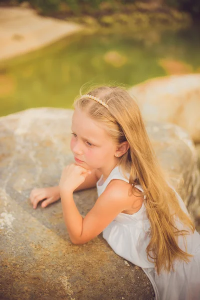 Retrato de una chica pensativa en un vestido blanco con el pelo largo con un borde en la playa un día de verano —  Fotos de Stock