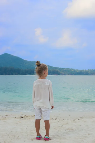 Девушка стоит на пляже и смотрит вдаль — стоковое фото