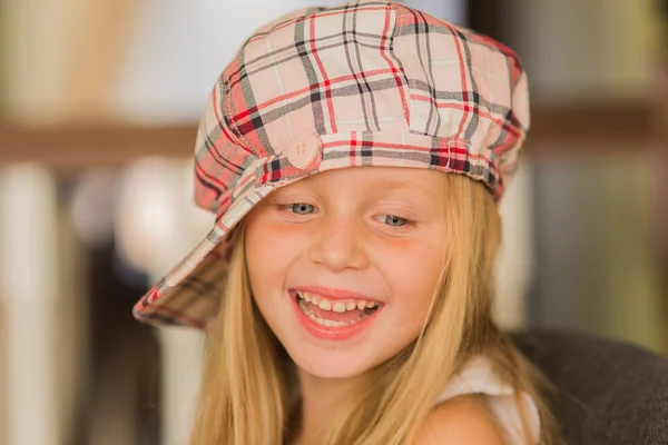 Retrato de uma menina sorridente em uma tampa quadriculada com cabelo comprido — Fotografia de Stock