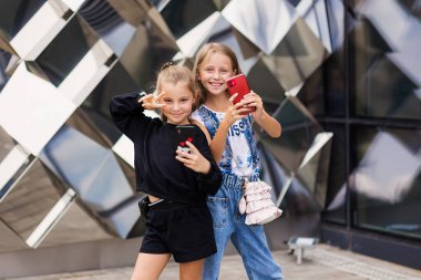 Mutlu kız arkadaşlar selfie çeker. Hoş kızlar. 10 yaşında. Şehirde yürüyüş yapıyorlar.