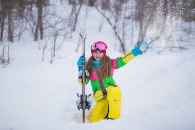 Kayak merkezindeki karlı bir dağda kayakçı bir kızın portresi. Aktif kendine güvenen beyaz kız portresi, gözlükler ve parlak takım elbise kışın ekstrem spor aktivitelerinin keyfini çıkarın.. 