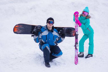 Mutlu kayakçı ve snowboardcu çift kayak merkezinde eğleniyor. Baba ve kızı kayak merkezinde. Kayak kış sporları konsepti 
