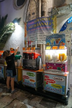 Peschici - 29 / 06 / 2021: Gece sokakta buzlu içecek makinesine su ekleyen kız