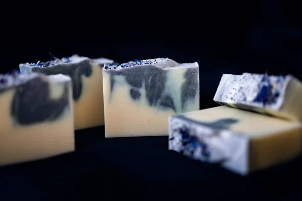 Koyu renk kumaşın üzerinde duran el yapımı sabun kalıpları.