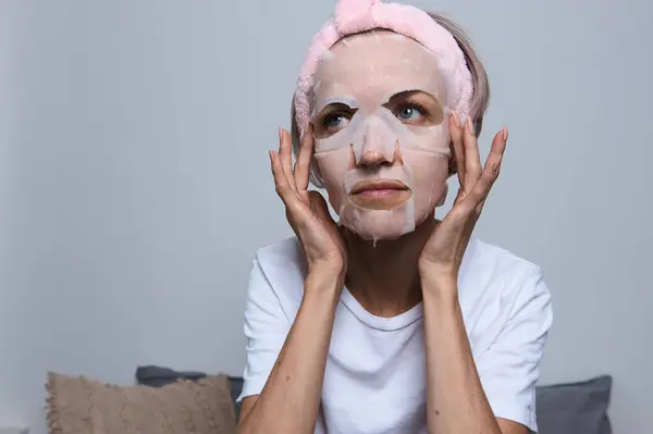 Kadın yüzüne maske takıyor.