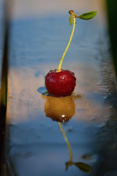 Yansıma ve gölge yağmur oluşturduktan sonra ahşap bir masa üzerinde bir Olgun Kiraz