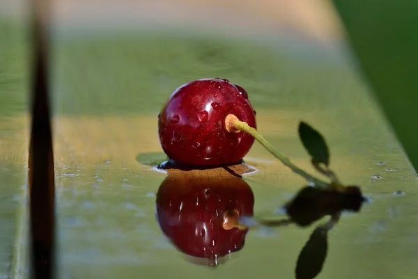 Yansıma ve gölge yağmur oluşturduktan sonra ahşap bir masa üzerinde bir Olgun Kiraz