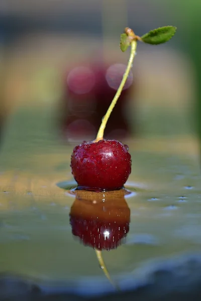 Yansıma ve gölge yağmur oluşturduktan sonra ahşap bir masa üzerinde bir Olgun Kiraz