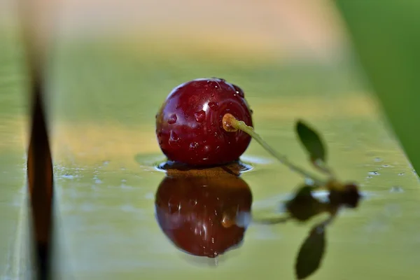 Yansıma ve gölge yağmur oluşturduktan sonra ahşap bir masa üzerinde bir Olgun Kiraz