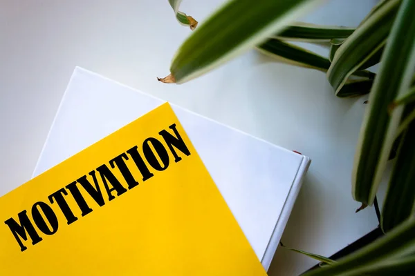 MOTIVATION a word written on yellow paper, next to torn shreds on a white background, the concept of success.