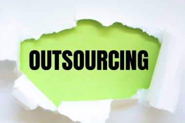 Yeşil yüzey ve dış kaynak kelimeleriyle yırtılmış beyaz kağıt.