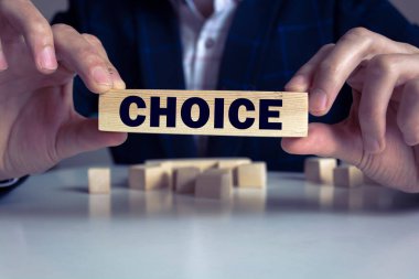 İş adamı elinde tahta blokla masa arkasında CHOICE iş sözcüğünü tutuyor. Görev, Vizyon ve temel değerler kavramı