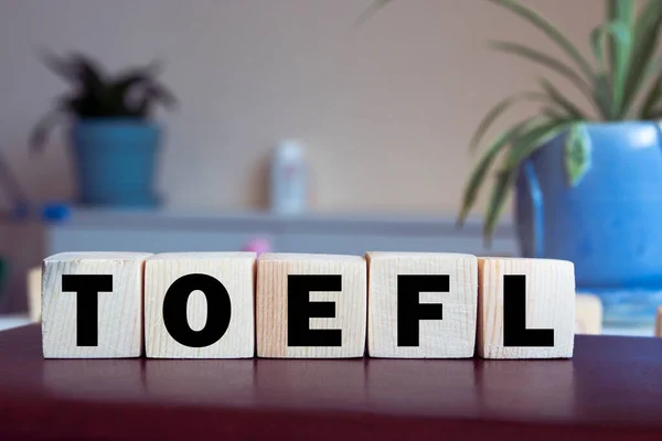 Üzerinde TOEFL harfleri olan oyuncak tahta bloklar. Arka planı aydınlık, seçici odaklı. TOEFL - yabancı dil olarak İngilizce sınavının kısaltılmışı