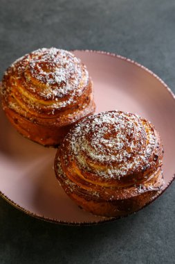 Tarçın ve hindistan cevizli limonlu çörekler gri bir masada pembe bir tabakta
