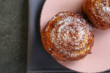 Tarçın ve hindistan cevizli limonlu çörekler gri bir masada pembe bir tabakta