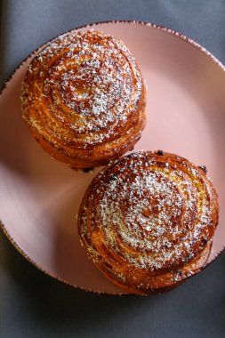 Tarçın ve hindistan cevizli limonlu çörekler gri bir masada pembe bir tabakta