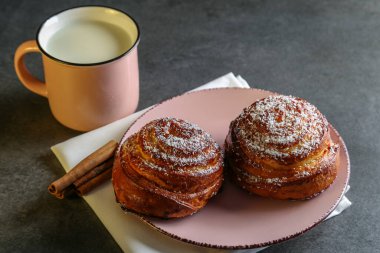 Tarçın ve hindistan cevizli limonlu çörekler gri bir masada pembe bir tabakta