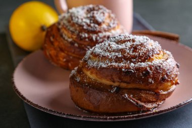 Tarçın ve hindistan cevizli limonlu çörekler gri bir masada pembe bir tabakta