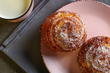 Tarçın ve hindistan cevizli limonlu çörekler gri bir masada pembe bir tabakta