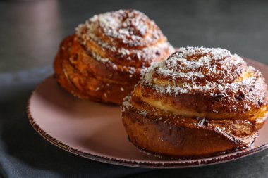 Tarçın ve hindistan cevizli limonlu çörekler gri bir masada pembe bir tabakta