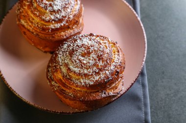Tarçın ve hindistan cevizli limonlu çörekler gri bir masada pembe bir tabakta