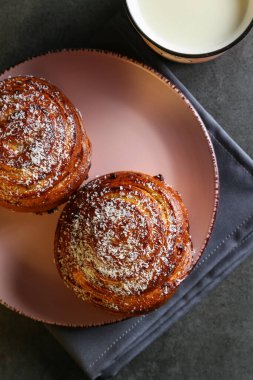 Tarçın ve hindistan cevizli limonlu çörekler gri bir masada pembe bir tabakta
