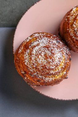 Tarçın ve hindistan cevizli limonlu çörekler gri bir masada pembe bir tabakta