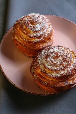 Tarçın ve hindistan cevizli limonlu çörekler gri bir masada pembe bir tabakta