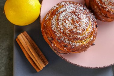 Tarçın ve hindistan cevizli limonlu çörekler gri bir masada pembe bir tabakta