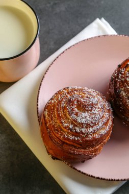 Tarçın ve hindistan cevizli limonlu çörekler gri bir masada pembe bir tabakta