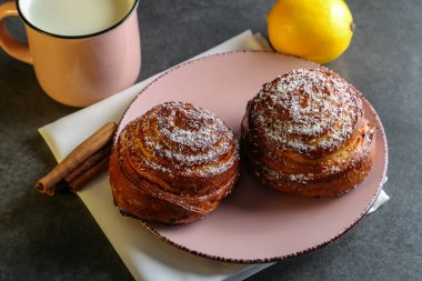 Tarçın ve hindistan cevizli limonlu çörekler gri bir masada pembe bir tabakta