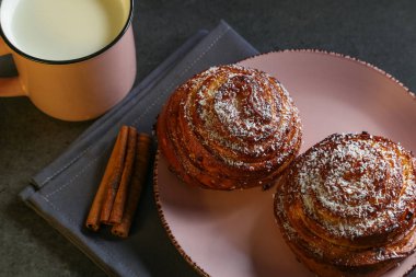 Tarçın ve hindistan cevizli limonlu çörekler gri bir masada pembe bir tabakta