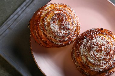 Tarçın ve hindistan cevizli limonlu çörekler gri bir masada pembe bir tabakta