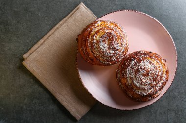 Tarçın ve hindistan cevizli limonlu çörekler gri bir masada pembe bir tabakta
