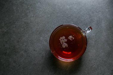 Gri seramik bir tezgahta, cam bir fincanda bir fincan sıcak, siyah çay..