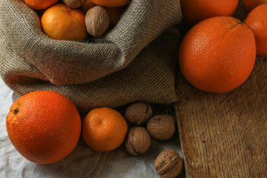 Olgun, lezzetli ve sulu portakallar, mandalinalar ve masada cevizler..